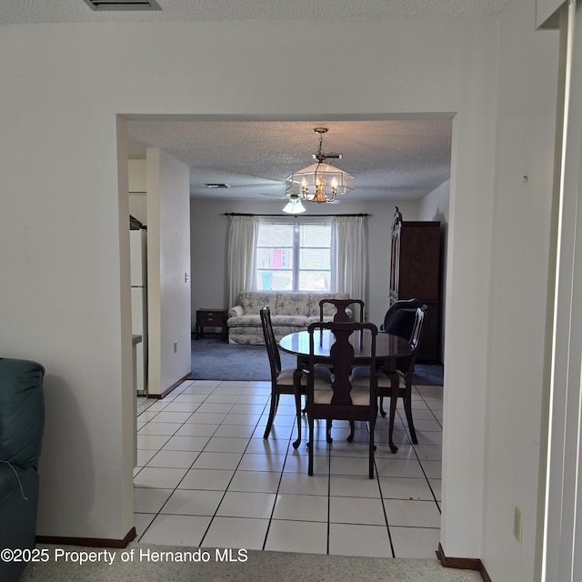 2226 Giralda Ave, Spring Hill, FL 34606 - dining area with a textured ceiling, a chandelier, light tile patterned floors, and baseboards