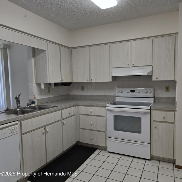 2226 Giralda Ave, Spring Hill, FL 34606 - kitchen with white appliances, under cabinet range hood, a sink, a textured ceiling, and light tile patterned floors