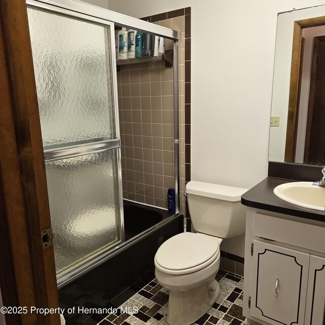 2226 Giralda Ave, Spring Hill, FL 34606 - full bathroom with vanity, toilet, bath / shower combo with glass door, and baseboards