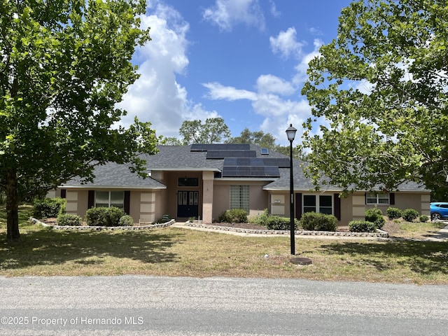 24 Black Willow Ct N, Homosassa, FL 34446 - view of front of house featuring solar panels, stucco siding, a front lawn, and roof with shingles