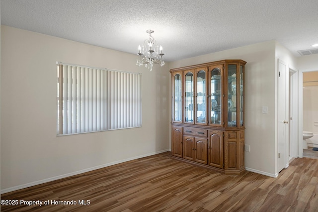 7630 Landmark Dr, Spring Hill, FL 34606 - unfurnished dining area featuring wood finished floors, a chandelier, baseboards, and a textured ceiling