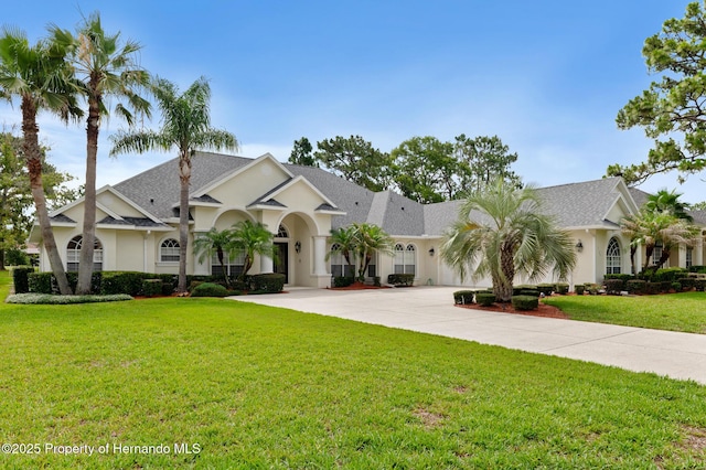 5182 Championship Cup Ln, Spring Hill, FL 34609 - view of front of house with curved driveway, stucco siding, a front yard, and an attached garage