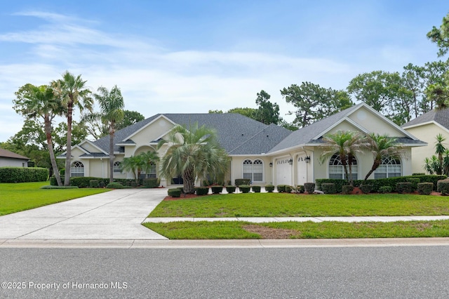 5182 Championship Cup Ln, Spring Hill, FL 34609 - view of front of home featuring driveway, a front yard, an attached garage, and stucco siding