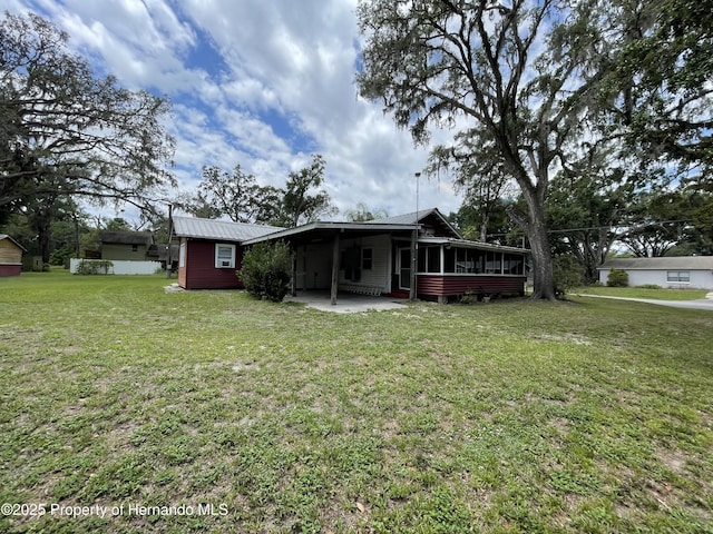 15306 Spokane Rd, Spring Hill Pasco, FL 34610 - back of house featuring a sunroom, a yard, and metal roof