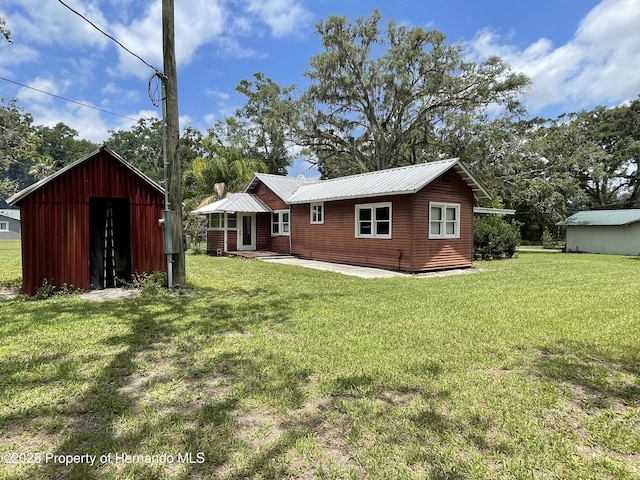 15306 Spokane Rd, Spring Hill Pasco, FL 34610 - back of house featuring a yard, an outbuilding, and metal roof