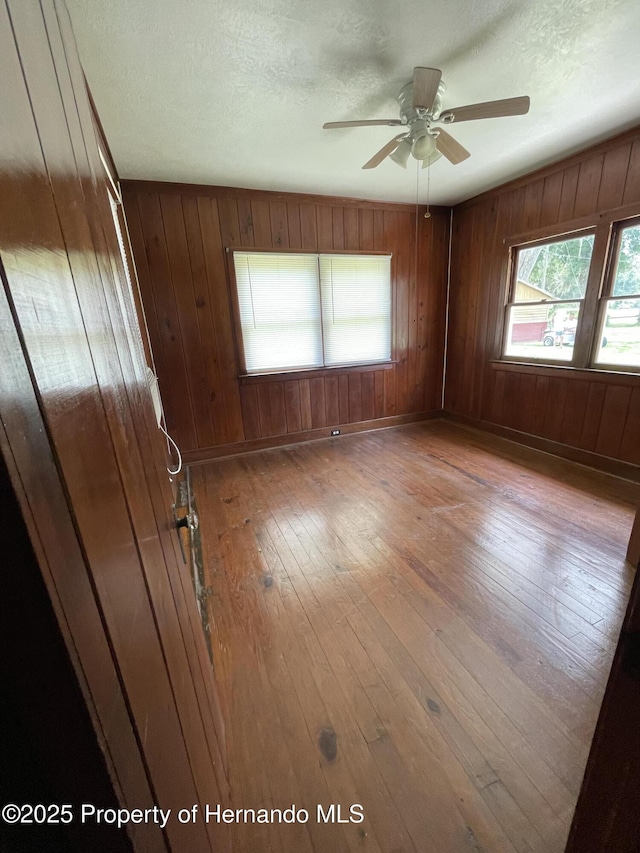 15306 Spokane Rd, Spring Hill Pasco, FL 34610 - unfurnished room with hardwood / wood-style floors, ceiling fan, wooden walls, and a textured ceiling