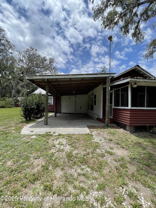 15306 Spokane Rd, Spring Hill Pasco, FL 34610 - back of house featuring dirt driveway, a carport, a sunroom, and a lawn
