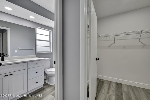 13406 Banyan Rd, Spring Hill, FL 34609 - bathroom featuring toilet, wood finished floors, vanity, a walk in closet, and recessed lighting