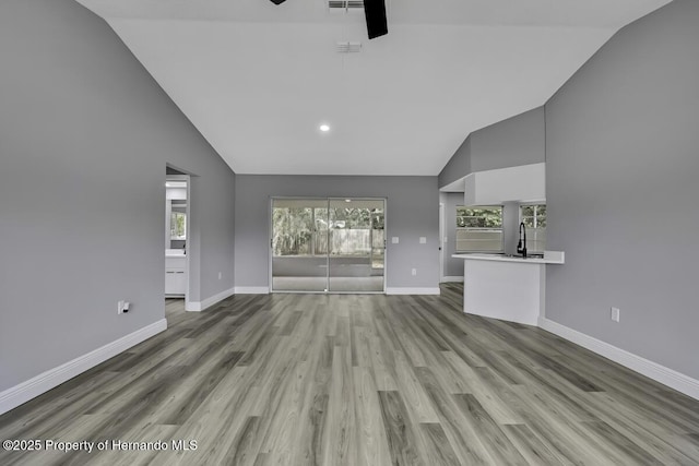 13406 Banyan Rd, Spring Hill, FL 34609 - unfurnished living room featuring wood finished floors, high vaulted ceiling, a sink, a ceiling fan, and baseboards