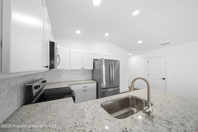 14376 Earline Ave, Weeki Wachee, FL 34614 - kitchen featuring appliances with stainless steel finishes, a sink, lofted ceiling, light stone counters, and decorative backsplash
