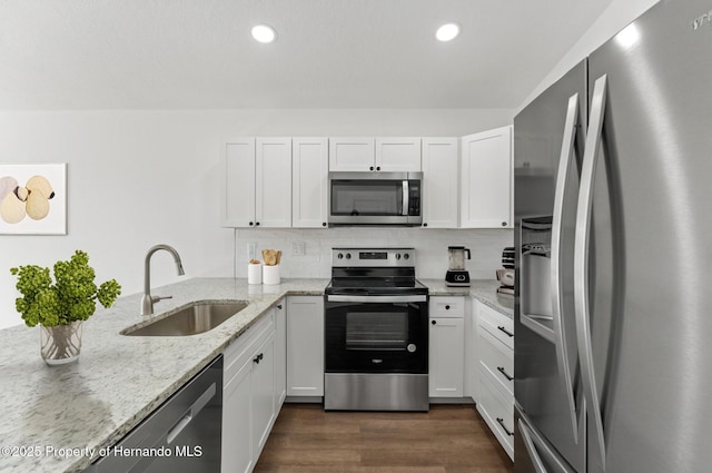 14376 Earline Ave, Weeki Wachee, FL 34614 - kitchen with stainless steel appliances, a sink, white cabinets, light stone countertops, and dark wood-type flooring
