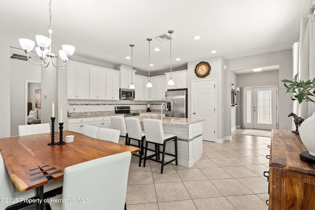 18620 Rococo Rd, Spring Hill Pasco, FL 34610 - kitchen with appliances with stainless steel finishes, light tile patterned floors, decorative backsplash, white cabinets, and a chandelier