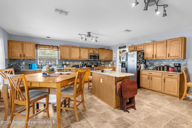 10457 Cranston St, Spring Hill, FL 34608 - kitchen featuring stainless steel appliances, tasteful backsplash, rail lighting, a kitchen island, and light stone counters