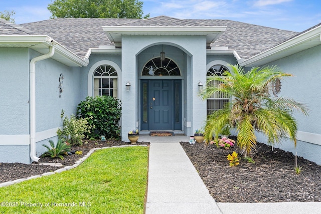 10457 Cranston St, Spring Hill, FL 34608 - property entrance with a shingled roof, stucco siding, and a lawn