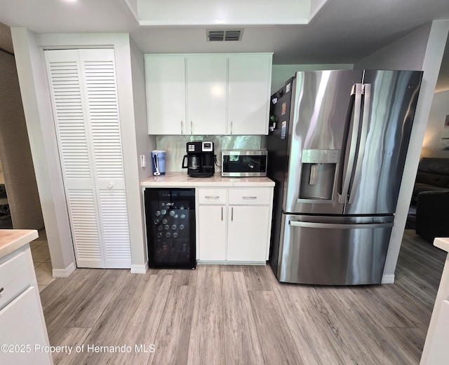2429 Birdie Ln, Spring Hill, FL 34606 - kitchen featuring stainless steel appliances, beverage cooler, light wood finished floors, and light countertops