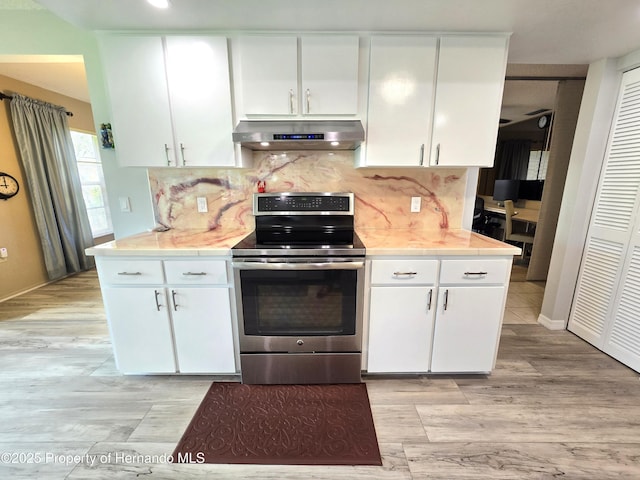 2429 Birdie Ln, Spring Hill, FL 34606 - kitchen featuring under cabinet range hood, stainless steel electric stove, light countertops, white cabinetry, and tasteful backsplash