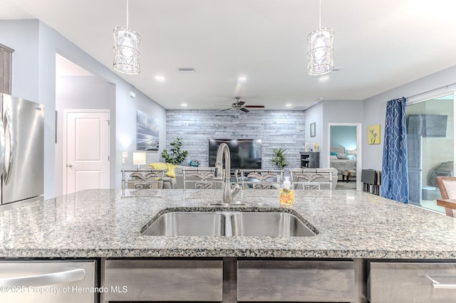 17679 Garsalaso Cir, Brooksville, FL 34604 - kitchen with appliances with stainless steel finishes, ceiling fan, open floor plan, light stone counters, and hanging light fixtures