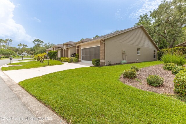 2481 Whispering Pines Ct, Spring Hill, FL 34606 - view of home's exterior featuring brick siding, an attached garage, a yard, and driveway