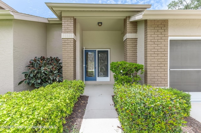 2481 Whispering Pines Ct, Spring Hill, FL 34606 - property entrance with an attached garage, brick siding, and stucco siding