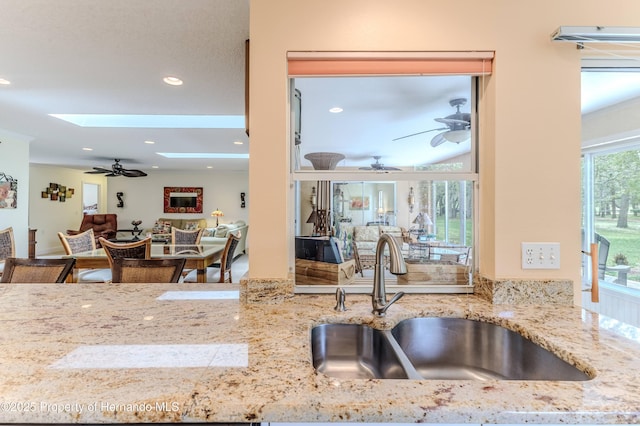 2481 Whispering Pines Ct, Spring Hill, FL 34606 - kitchen featuring a sink, ceiling fan, a skylight, recessed lighting, and light stone countertops