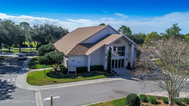 2481 Whispering Pines Ct, Spring Hill, FL 34606 - view of front of home with roof with shingles, stucco siding, and a front lawn