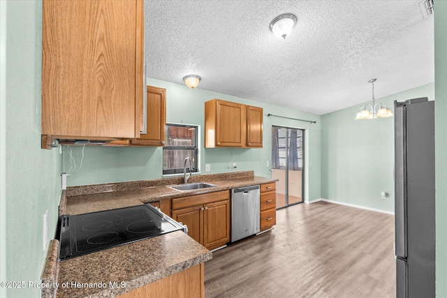 2450 Ambassador Ave, Spring Hill, FL 34609 - kitchen with stainless steel appliances, a sink, light wood-type flooring, a textured ceiling, and a chandelier