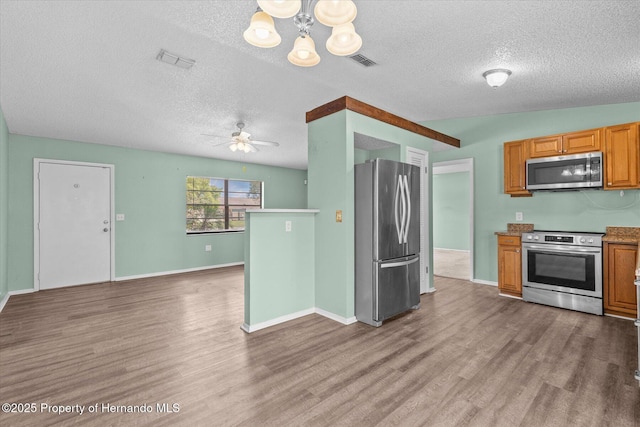 2450 Ambassador Ave, Spring Hill, FL 34609 - kitchen with stainless steel appliances, a textured ceiling, light wood finished floors, a chandelier, and a ceiling fan