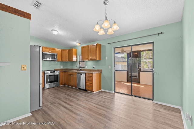 2450 Ambassador Ave, Spring Hill, FL 34609 - kitchen with stainless steel appliances, a textured ceiling, wood finished floors, lofted ceiling, and a chandelier