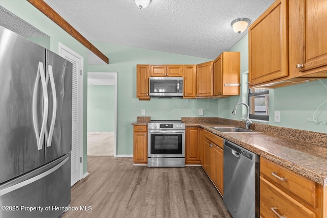 2450 Ambassador Ave, Spring Hill, FL 34609 - kitchen featuring appliances with stainless steel finishes, a sink, dark wood finished floors, vaulted ceiling, and a textured ceiling