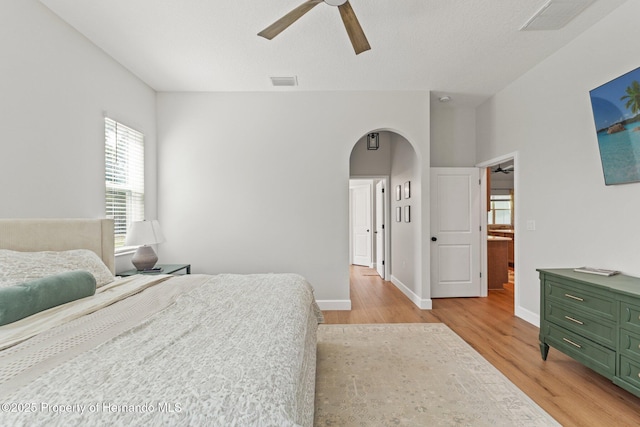 27295 Tarbel Rd, Brooksville, FL 34602 - bedroom featuring arched walkways, light wood finished floors, baseboards, and ceiling fan