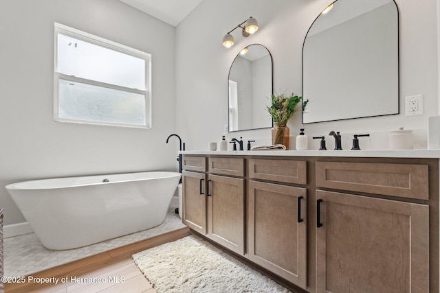 27295 Tarbel Rd, Brooksville, FL 34602 - bathroom with wood finished floors, double vanity, a freestanding bath, and baseboards