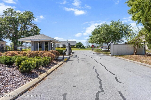10485 S Drew Bryant Cir, Floral City, FL 34436 - view of asphalt street featuring a gated entry, curbs, a gate, and traffic signs