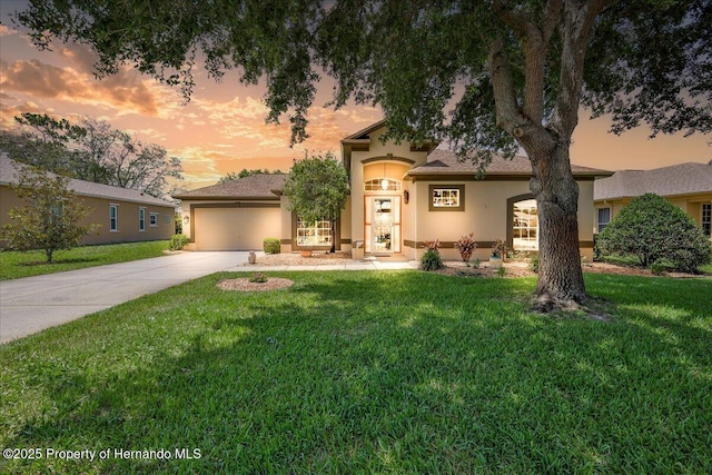 9406 Burnam Dr, Weeki Wachee, FL 34613 - view of front of property with stucco siding, driveway, a yard, and a garage
