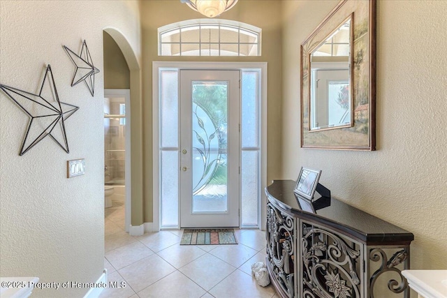 9406 Burnam Dr, Weeki Wachee, FL 34613 - foyer with arched walkways, a textured wall, and light tile patterned floors