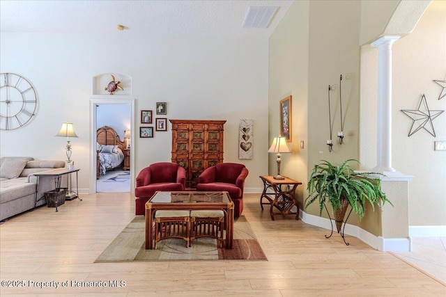 9406 Burnam Dr, Weeki Wachee, FL 34613 - living area with ornate columns, wood finished floors, a high ceiling, and baseboards