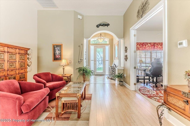 9406 Burnam Dr, Weeki Wachee, FL 34613 - living area with light wood-style floors, baseboards, arched walkways, and a high ceiling