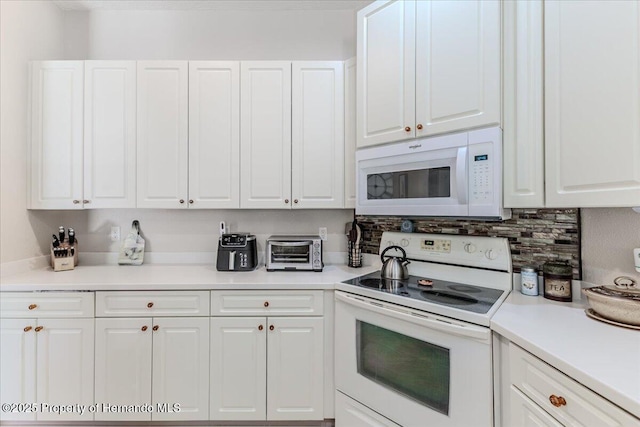9406 Burnam Dr, Weeki Wachee, FL 34613 - kitchen featuring white appliances, white cabinets, backsplash, and light countertops
