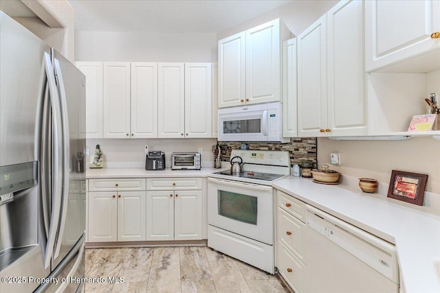9406 Burnam Dr, Weeki Wachee, FL 34613 - kitchen with white appliances, white cabinets, light countertops, light marble finish flooring, and tasteful backsplash
