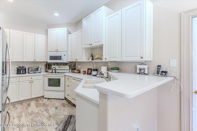 9406 Burnam Dr, Weeki Wachee, FL 34613 - kitchen with white appliances, a sink, a peninsula, white cabinetry, and recessed lighting
