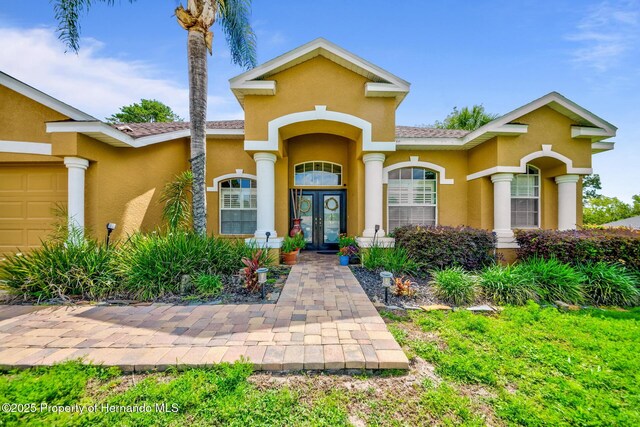 11422 Warm Wind Way, Weeki Wachee, FL 34613 - entrance to property with stucco siding, french doors, and a garage