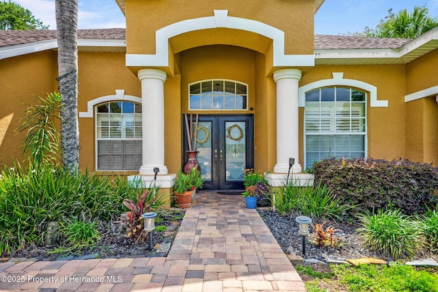 11422 Warm Wind Way, Weeki Wachee, FL 34613 - entrance to property with french doors, stucco siding, and a shingled roof