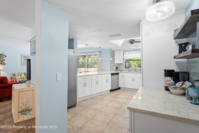 9766 W Smokey Ln, Crystal River, FL 34429 - kitchen featuring appliances with stainless steel finishes, a sink, white cabinets, decorative backsplash, and light tile patterned floors