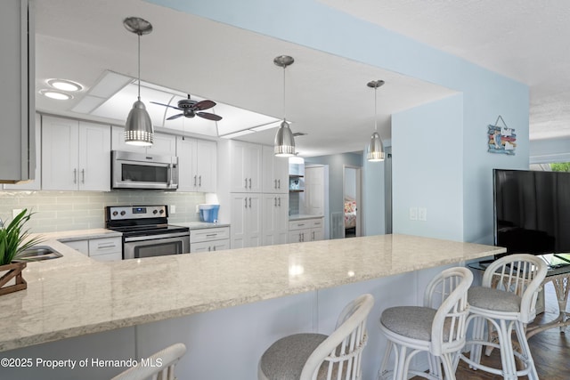 9766 W Smokey Ln, Crystal River, FL 34429 - kitchen featuring stainless steel appliances, light stone countertops, a sink, white cabinets, and backsplash