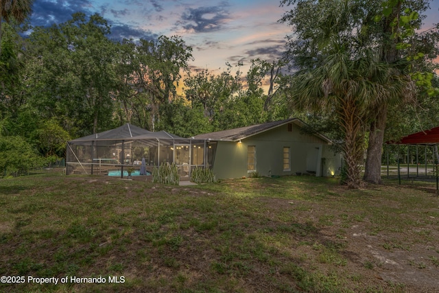 9766 W Smokey Ln, Crystal River, FL 34429 - back of property at dusk with an outdoor pool, a yard, and a lanai