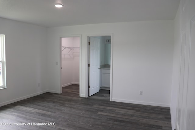 2001 W Royal Palm Dr, Dunnellon, FL 34434 - unfurnished bedroom featuring dark wood-type flooring, a spacious closet, baseboards, a closet, and connected bathroom