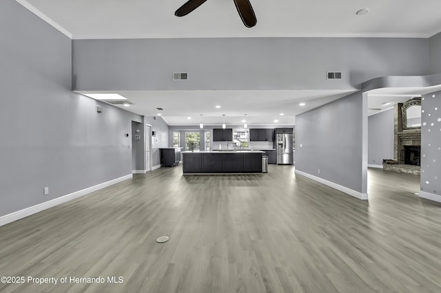 10277 Rosetti Ct, Spring Hill, FL 34608 - living room with light wood-type flooring, a ceiling fan, baseboards, ornamental molding, and a large fireplace