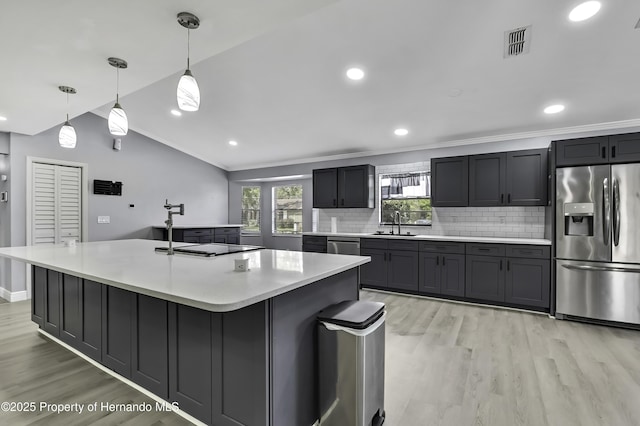 10277 Rosetti Ct, Spring Hill, FL 34608 - kitchen with appliances with stainless steel finishes, a sink, light wood finished floors, backsplash, and light countertops