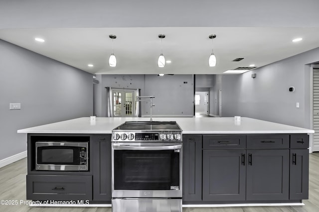 10277 Rosetti Ct, Spring Hill, FL 34608 - kitchen featuring appliances with stainless steel finishes, light wood-style flooring, light countertops, decorative light fixtures, and gray cabinets