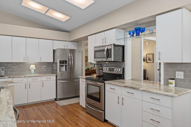 2486 Deer Trail Ln, Spring Hill, FL 34606 - kitchen with appliances with stainless steel finishes, backsplash, vaulted ceiling, white cabinets, and light wood-style floors