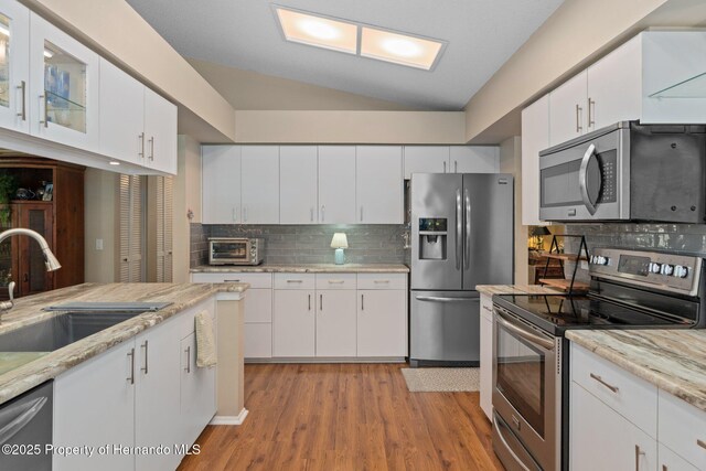 2486 Deer Trail Ln, Spring Hill, FL 34606 - kitchen featuring appliances with stainless steel finishes, a sink, lofted ceiling, backsplash, and white cabinetry